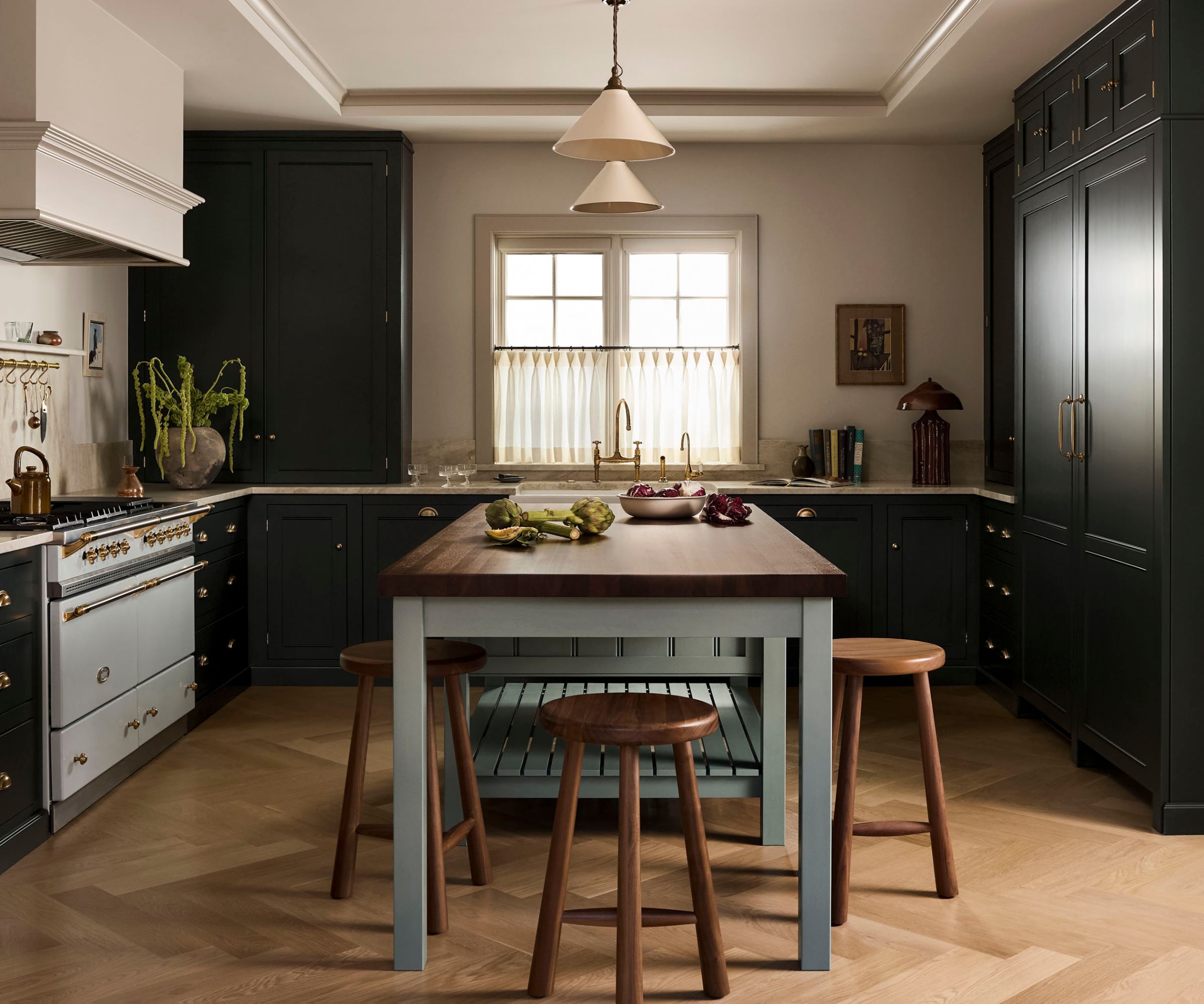 A Federal home kitchen with black countertops with Taj Mahal quartzite countertops and a blue freestanding island with wooden countertops