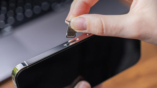 A person inserting a SIM card into an iPhone
