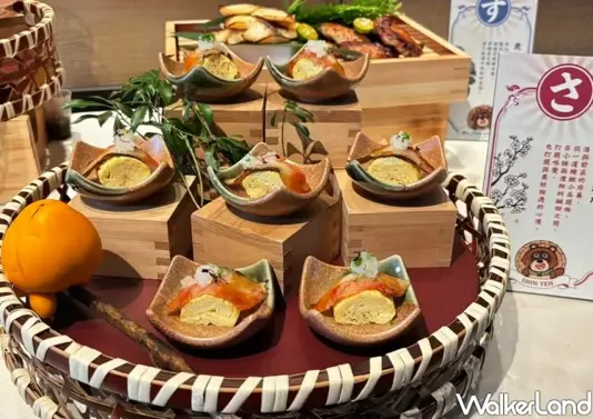 ▲以傳統五味為靈感設計精緻日式小品，精美的鰻魚玉子燒整齊排列在竹籃中，旁邊擺放著福丸角色的可愛告示牌。