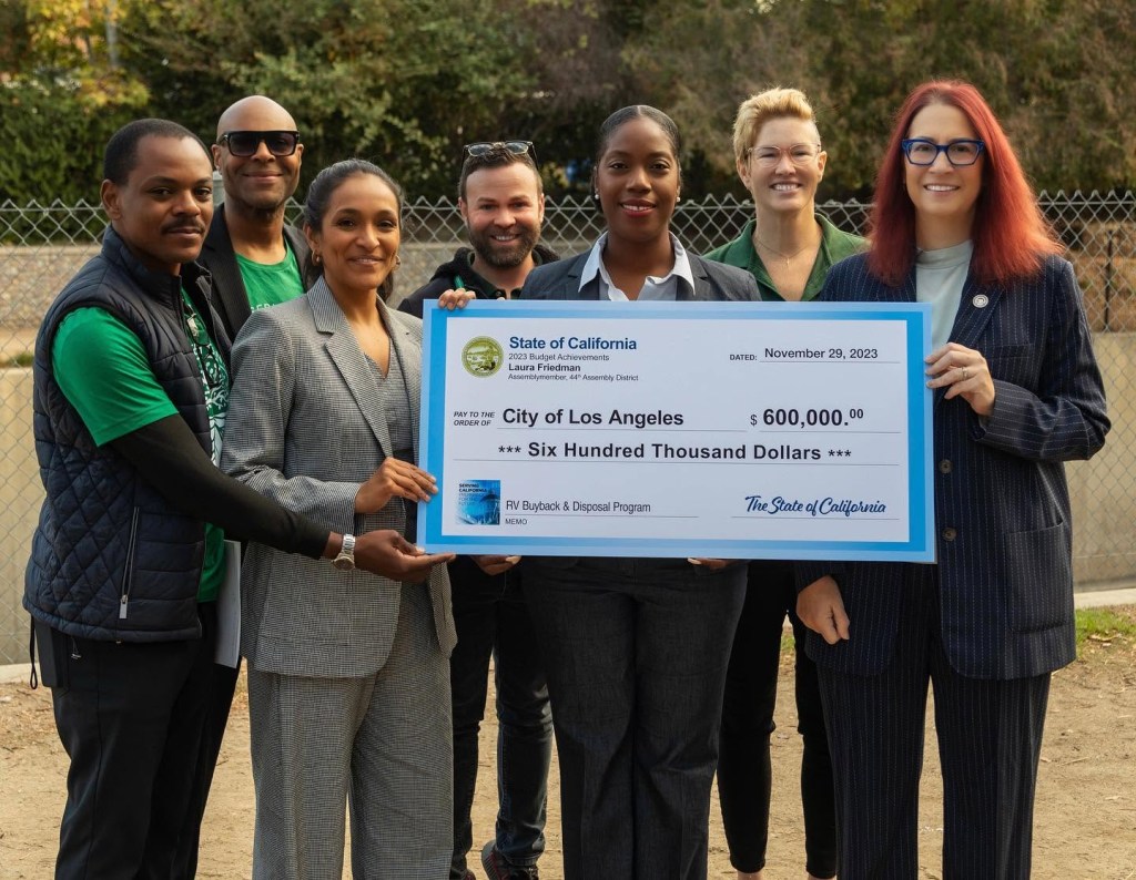 Nithya Raman holds a check for $600,000 on December 6, 2023. Representative Laura Friedman