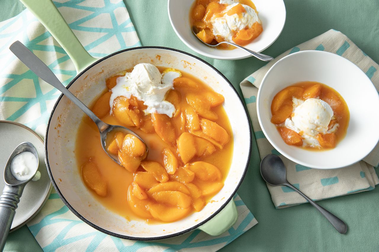 overhead on a dutch oven and two servings of tipsy peaches served with vanilla ice cream