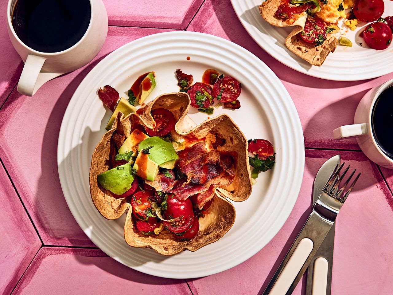 Overhead shot of breakfast burrito bowls on a pink table