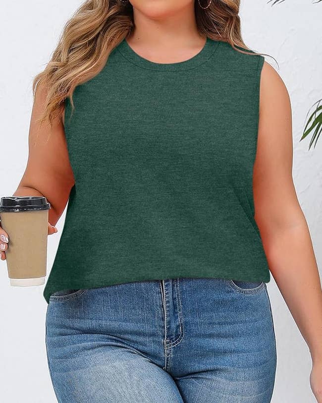 Person in sleeveless top and jeans holding a coffee cup. Casual outfit, suitable for everyday wear