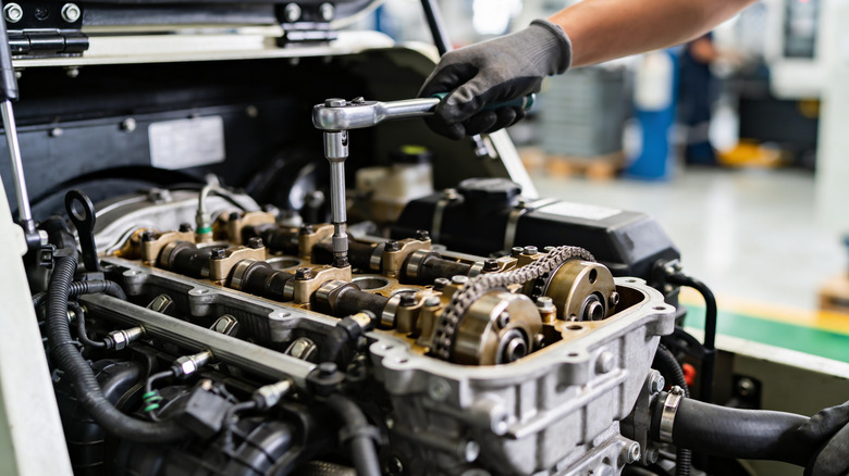 Close up view of mechanic working on four-cylinder engine.