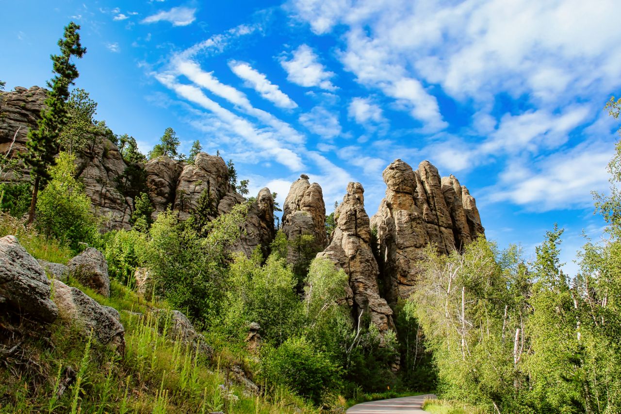 Rock formations surrounded by trees under a partly cloudy sky