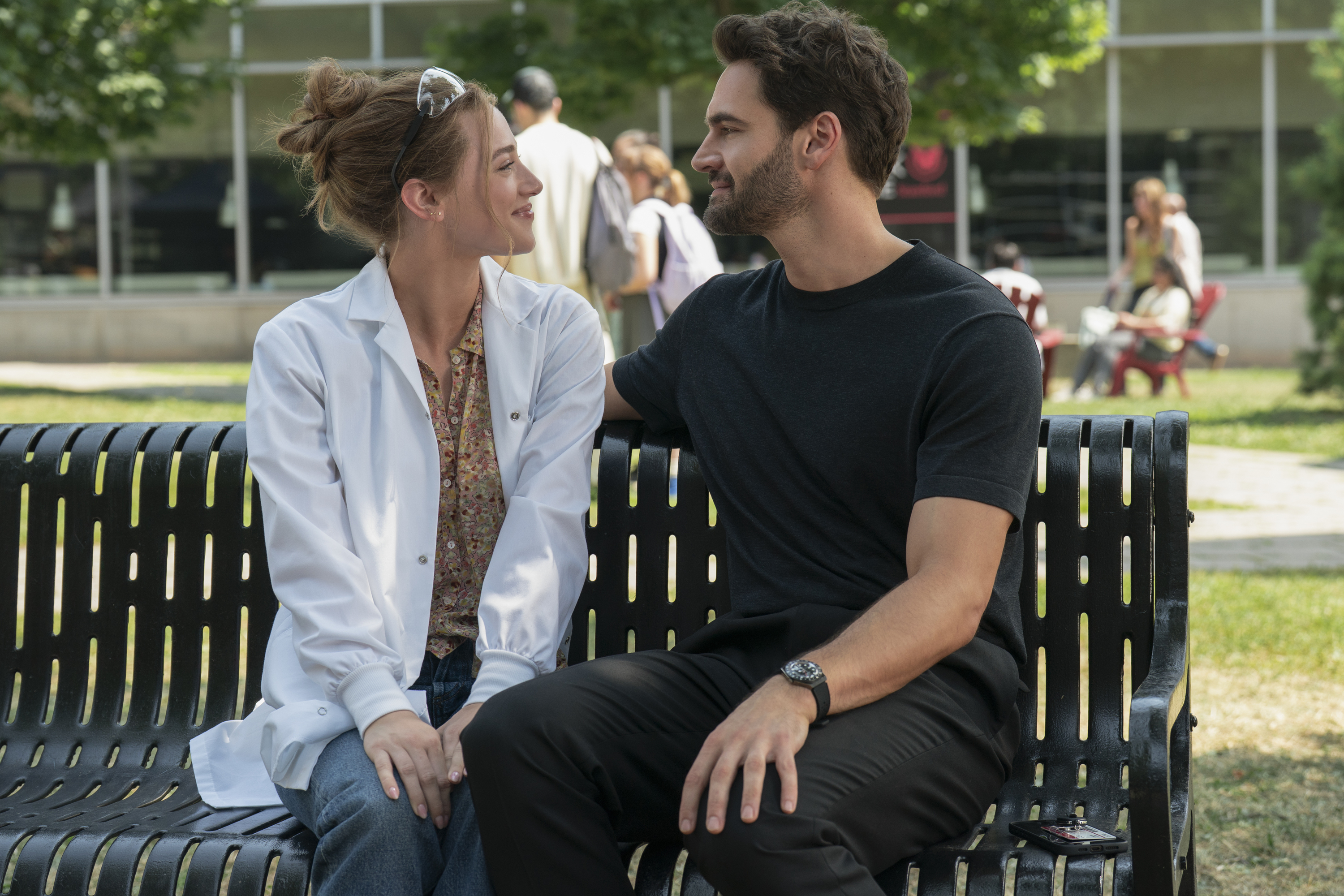 lili reinhart as olive and tom bateman as adam sitting on a bench in the love hypothesis movie