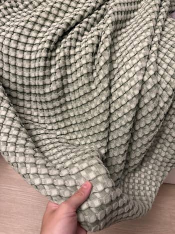 Reviewer showing waffle fabric of the cooling blanket in a sage green color