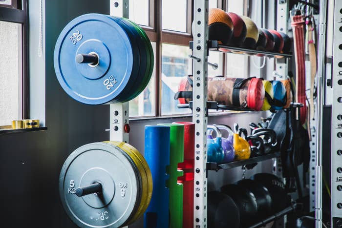 A well-equipped gym corner with various weights, kettlebells, and exercise balls organized near a window