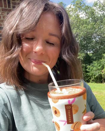 Reviewer smiling and drinking from an iced drink inside the JavaSok