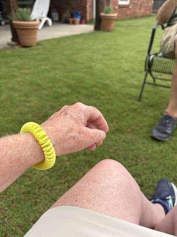 Reviewer sitting outside and wearing the spiral mosquito repelling bracelet in yellow