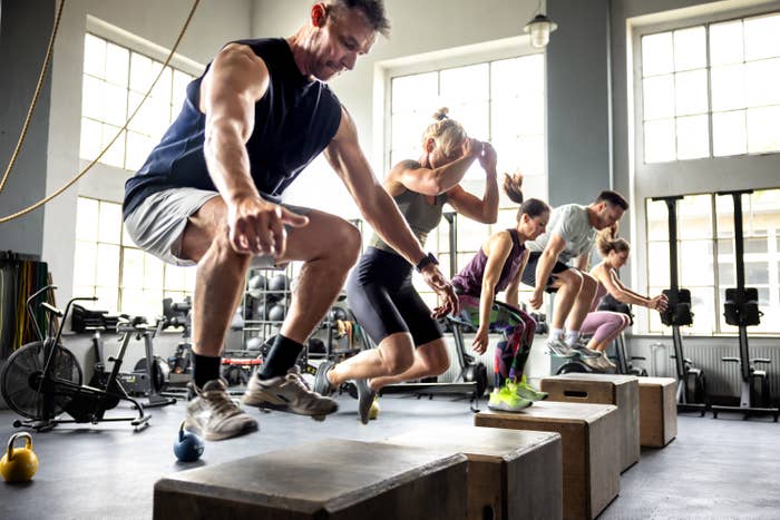People in a gym performing box jumps during a high-intensity workout class