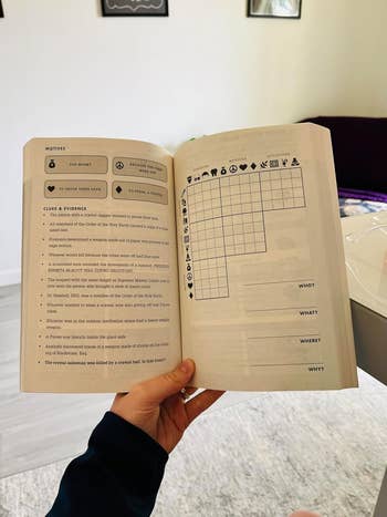 Person holding an open book showing a puzzle grid and a list of motives and evidence related to solving a mystery