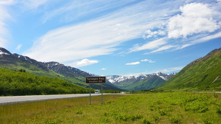 A brown sign indicated Turnagain Pass in Alaska with mountains in the distance.