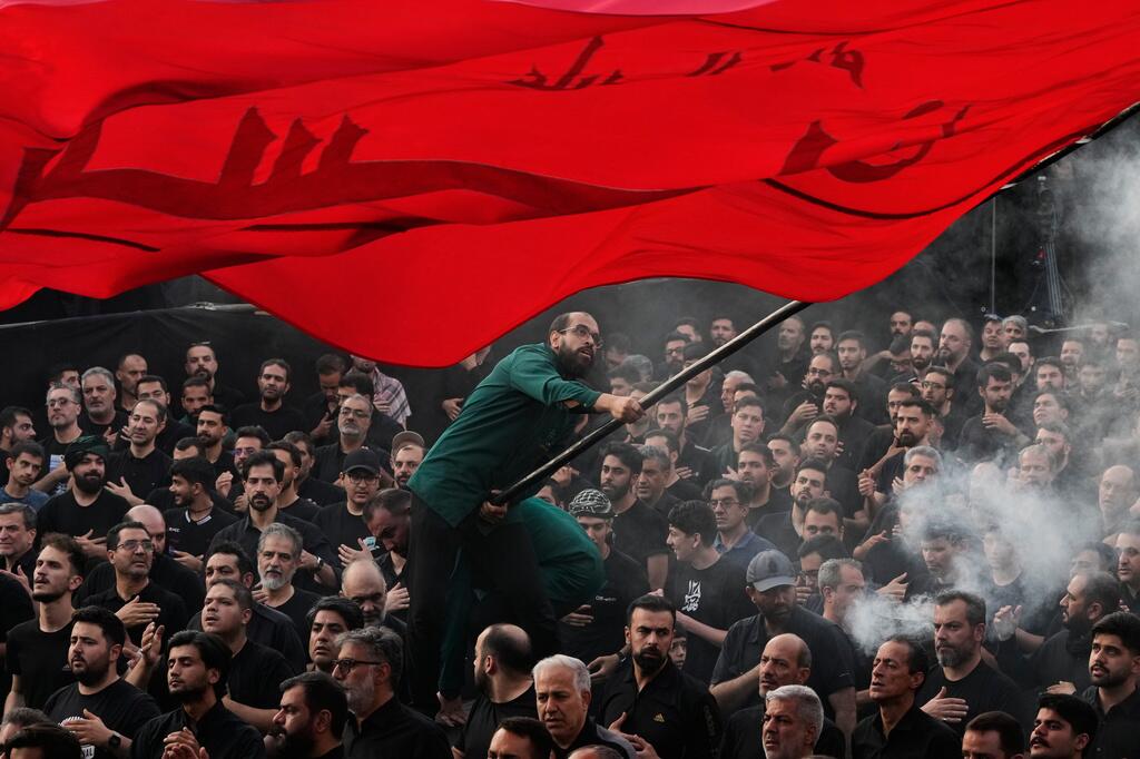 Un hombre ondea una bandera religiosa mientras un grupo de hombres se golpean el pecho durante una ceremonia de duelo en Teherán, Irán, el jueves 18 de junio de 2026, antes del Ashura, la festividad que conmemora el martirio en el siglo VII del nieto del profeta Mahoma, Husayn, quien murió en la batalla de Karbala, en el actual Irak. ((Vahid Salemi/AP Photo/Vahid Salemi))