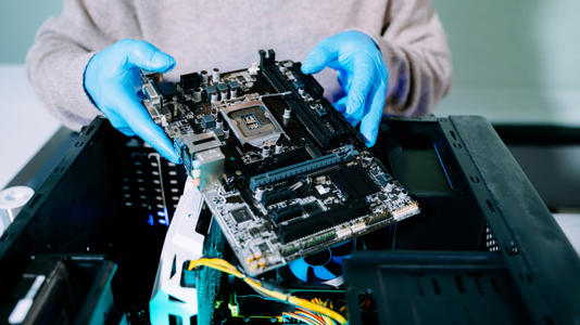 Person installing a motherboard into a desktop PC case during a computer build.