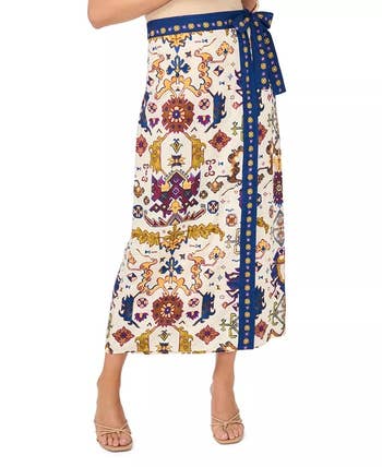 Person modeling a patterned midi skirt with a detailed design and a tied waistband, styled for a fashion shopping feature