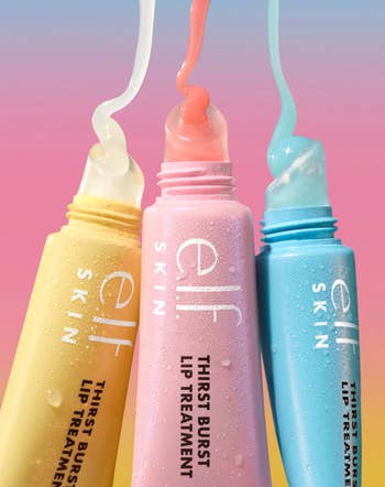 Three tubes of e.l.f. Skin Thirst Burst Lip Treatment in pastel packaging, with product oozing out, against a gradient background