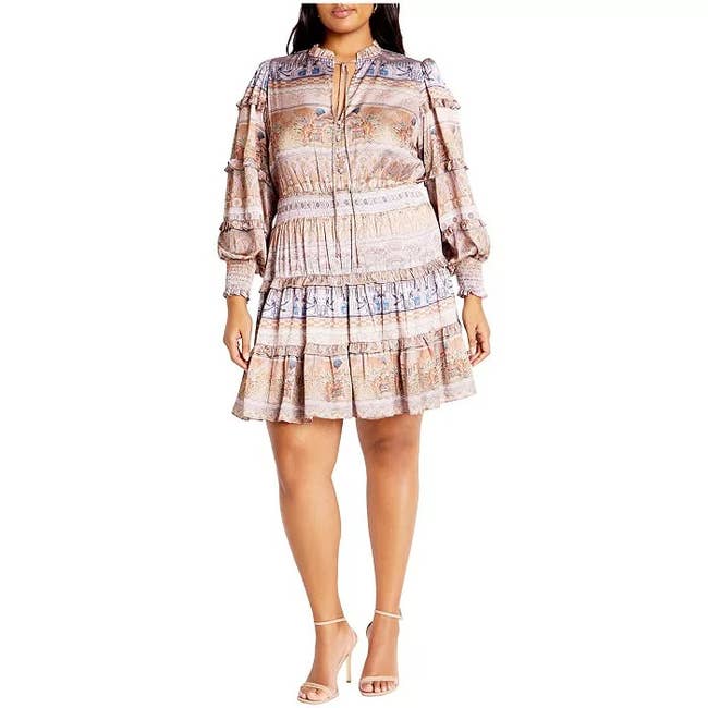 Person wearing a boho-style dress with long sleeves and tiered skirt, paired with strappy sandals