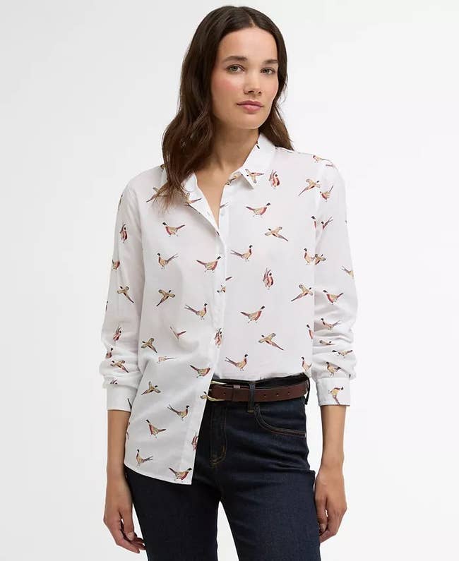 Person wearing a long-sleeve shirt with a crane pattern, paired with dark jeans