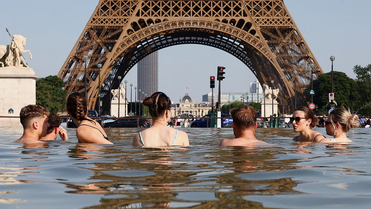 People cool off in the Trocadero Fountain next to the Eiffel Tower as temperatures rise during a heatwave affecting much of France in Paris on June 22, 2026.