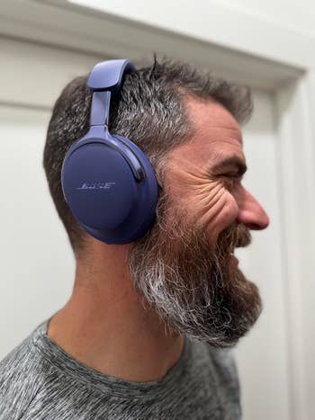 Man wearing over-ear headphones, smiling, side profile