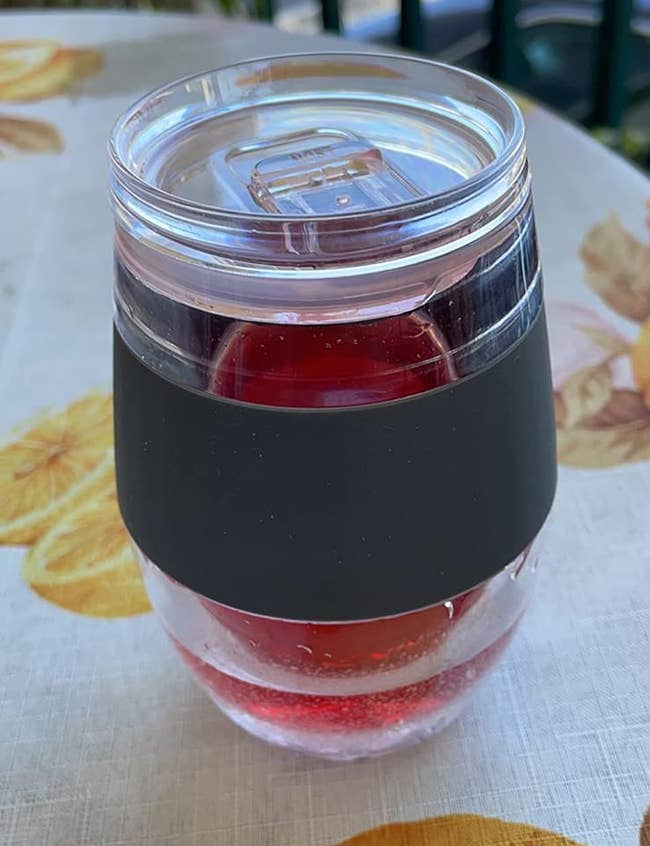 Clear plastic cup with a black band contains a red drink