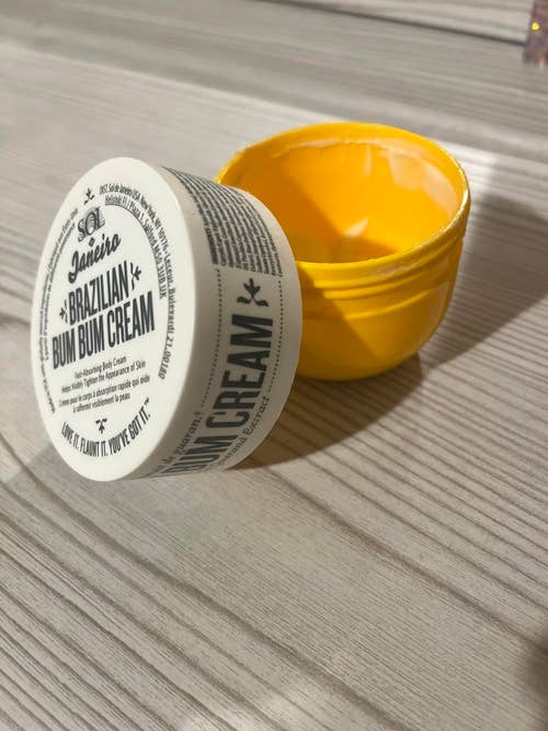 Open jar of Sol de Janeiro Brazilian Bum Bum Cream on a wooden surface. Label includes product details