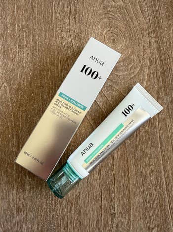 Anua 100+ toner hyaluron cream with box on wooden surface, showcasing skincare product packaging for hydration and pore care