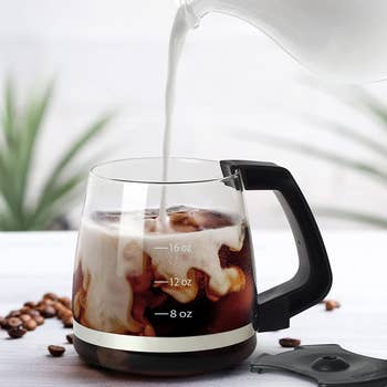 milk being poured into the coffee-filled mug