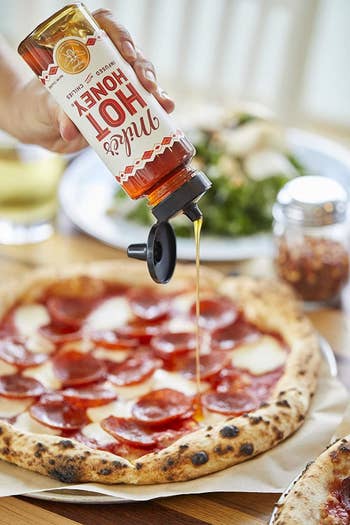 Person drizzling the honey pizza