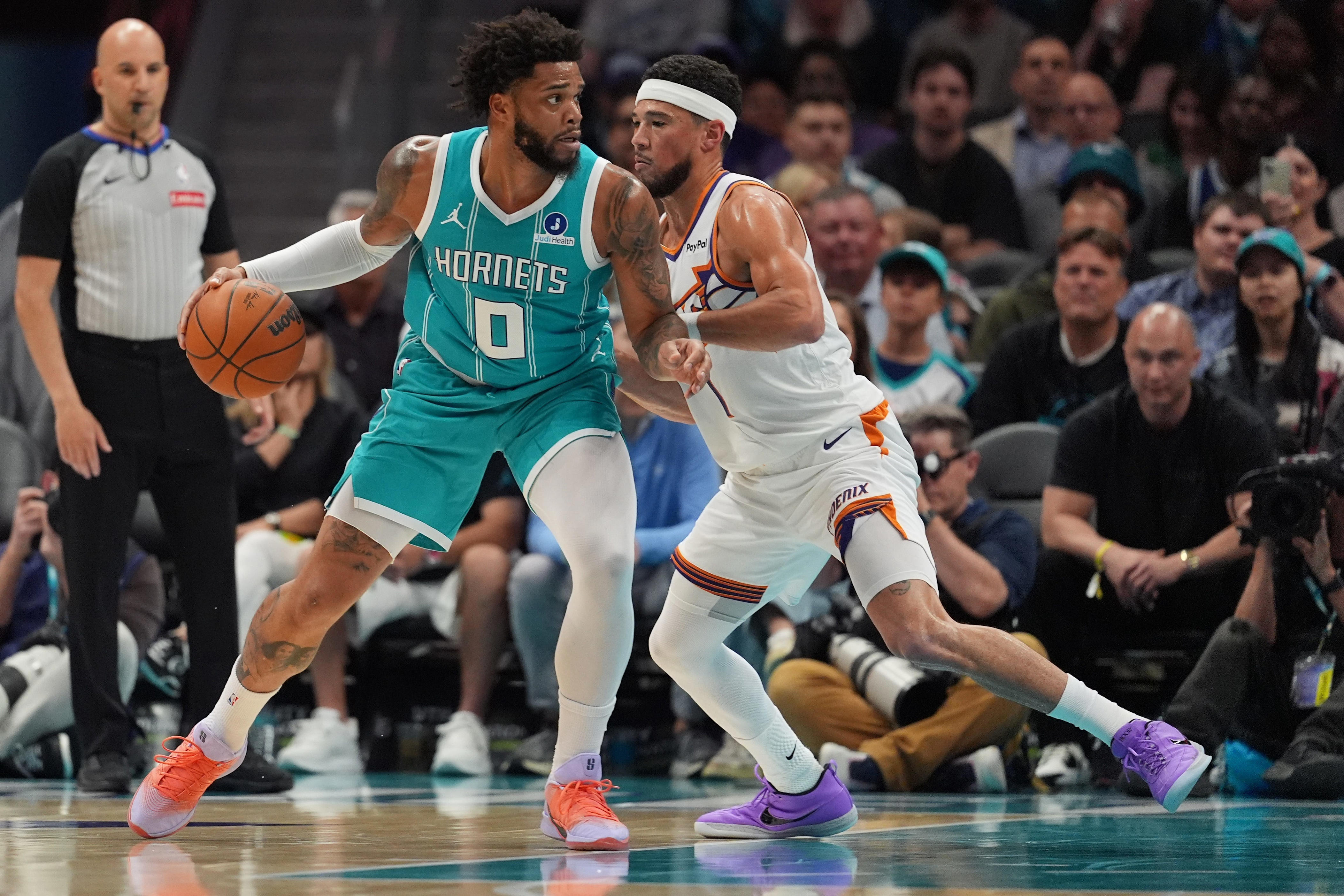 Apr 2, 2026; Charlotte, North Carolina, USA; Charlotte Hornets forward Miles Bridges (0) works the ball against Phoenix Suns guard Devin Booker (1)during the first quarter at Spectrum Center. Mandatory Credit: Jim Dedmon-Imagn Images