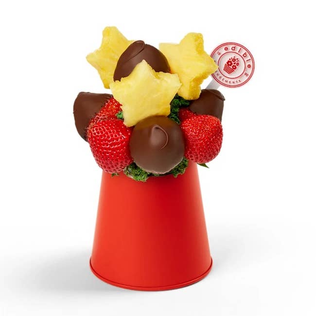 Chocolate-dipped strawberries and star-shaped pineapples arranged in a red container, perfect as a decorative edible gift