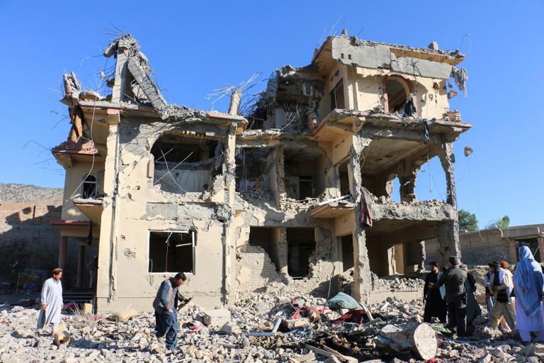 Residents and Taliban members gather near a destroyed building following an airstrike that the Taliban say was carried out by Pakistan's security forces, in Samkani district, Afghanistan (Reuters)