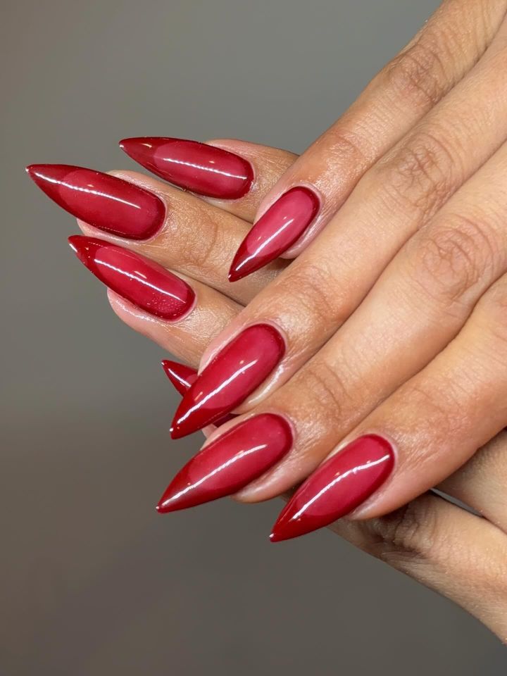 Manicured hands with long pointed nails with red French tips