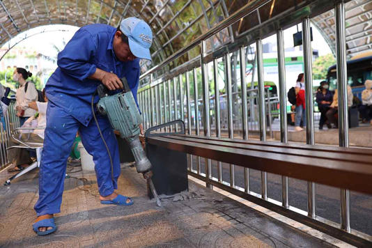Các công nhân khẩn trương kiểm tra, sửa chữa ghế ngồi, đá vỉa hè bị chênh, vỡ tại khu vực chờ xe buýt. Ảnh: Như Quỳnh