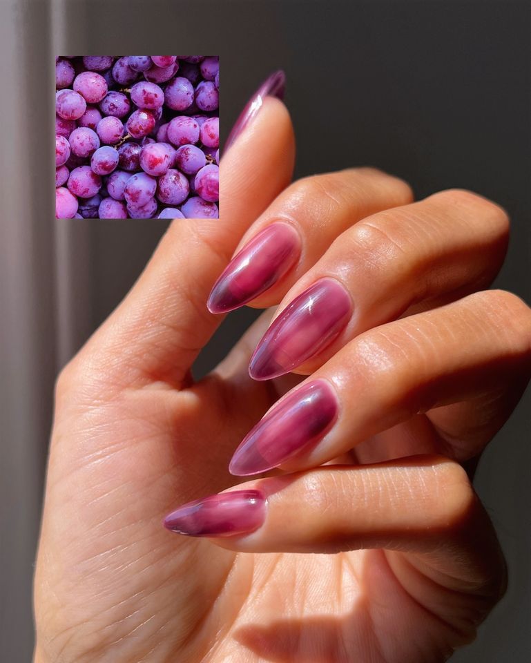 Hand with nail art inspired by grapes closeup view of the design and a small inset image of grapes