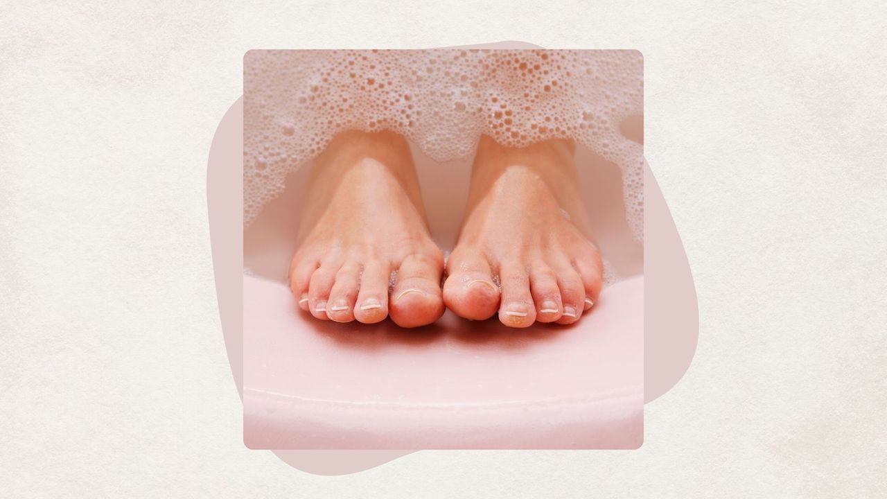 a woman's feet emerging from bubblu water in a pink foot bath