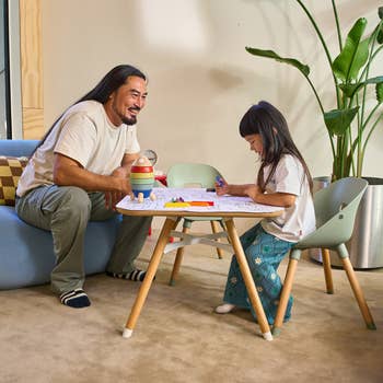 Adult and child sitting at a small table playing