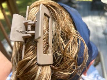 Close-up of a hair claw clip holding damp, styled hair. Person wears a headband, suggesting a casual, practical hairstyle for everyday wear