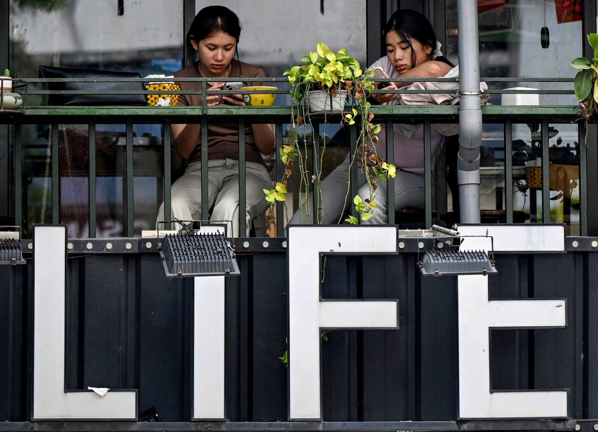 Women look at their phones at a cafe in Hanoi on Monday. Photo: AFP(