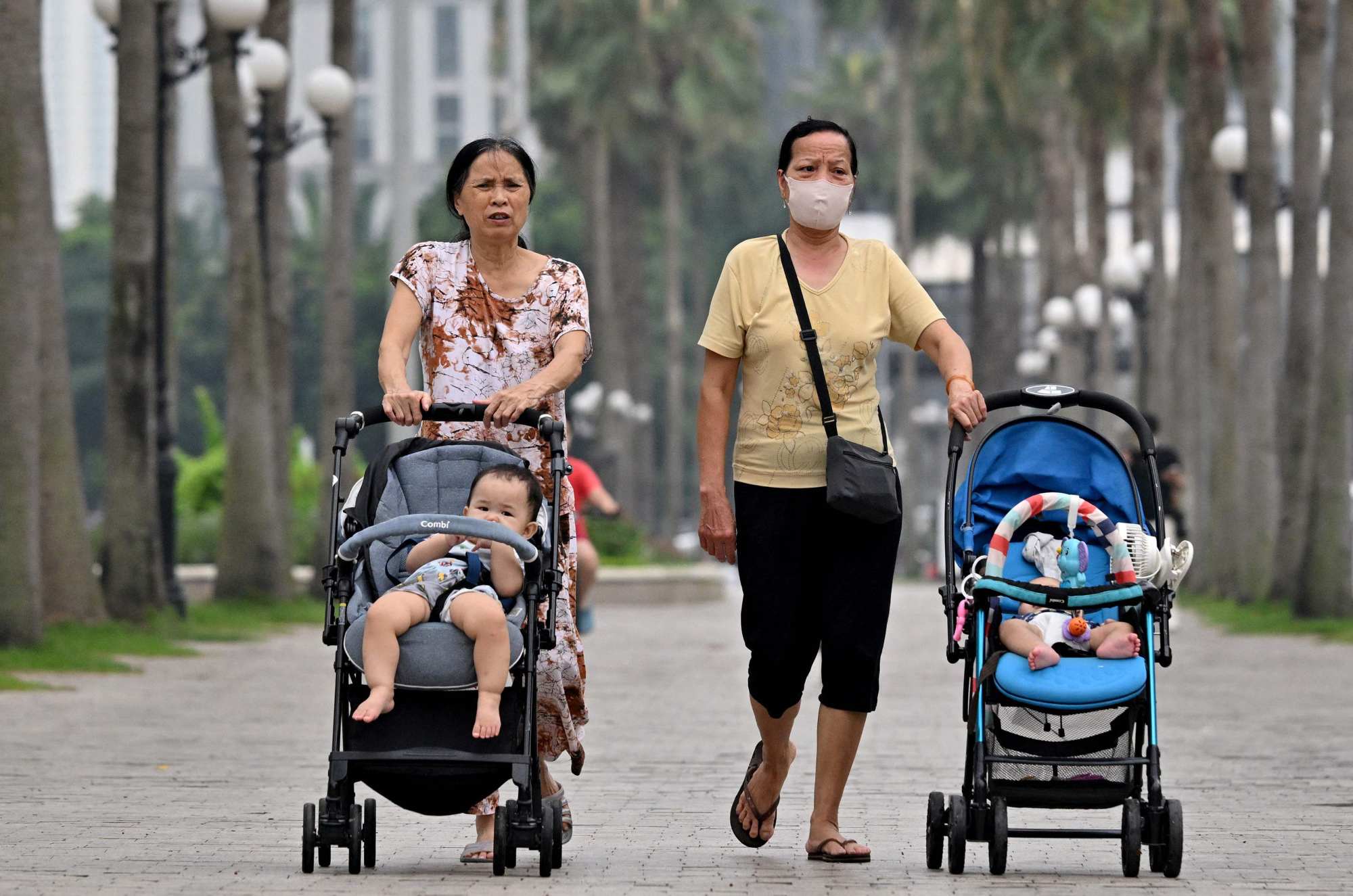 Women push children in strollers along a pavement in Hanoi on Monday. Photo: AFP
