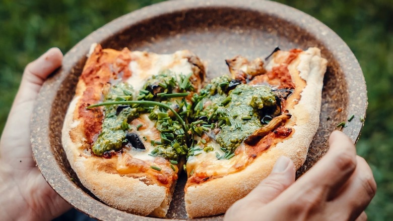 A person holding a plate of gourmet pizza as the Tomorrowland festival