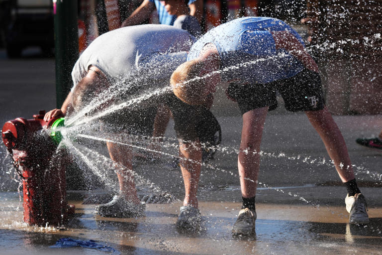 People enjoy the spray of cool water in front of a Chicago Fire Department on Tuesday. (Nam Y. Huh / AP)