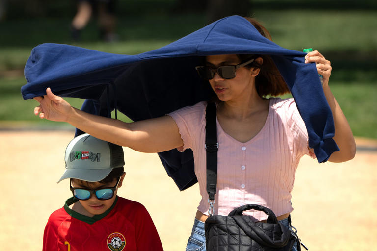 Visitors use a jacket for shade as they walk at the Great American State Fair on the National Mall on Tuesday. (Mark Schiefelbein / AP)