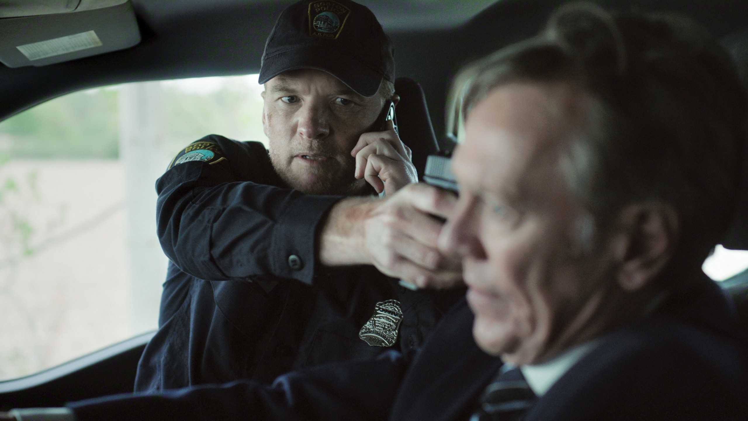 Sam Worthington as David Burroughs pointing a gun at a driver in Harlan Coben's I Will Find You (2026)