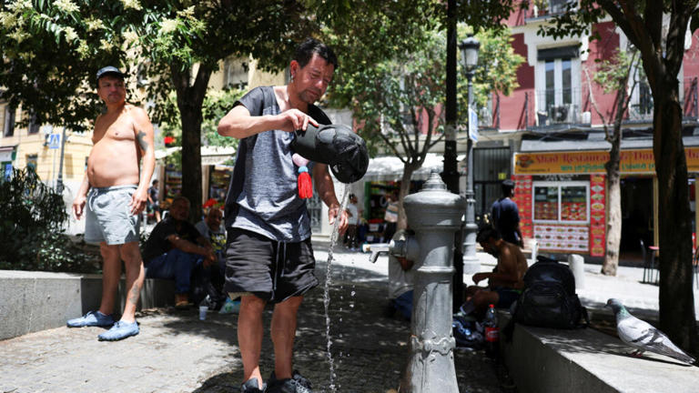 A man rinses his hat with water to cool off during a hot day amid a heatwave in Madrid, Spain on June 23, 2026.