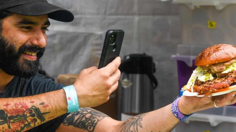 A person at Outside Lands taking a picture of their burger