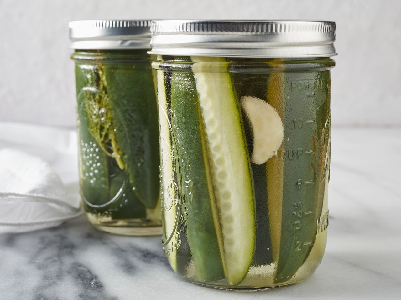 Jars of pickled cucumbers with garlic and dill visible inside