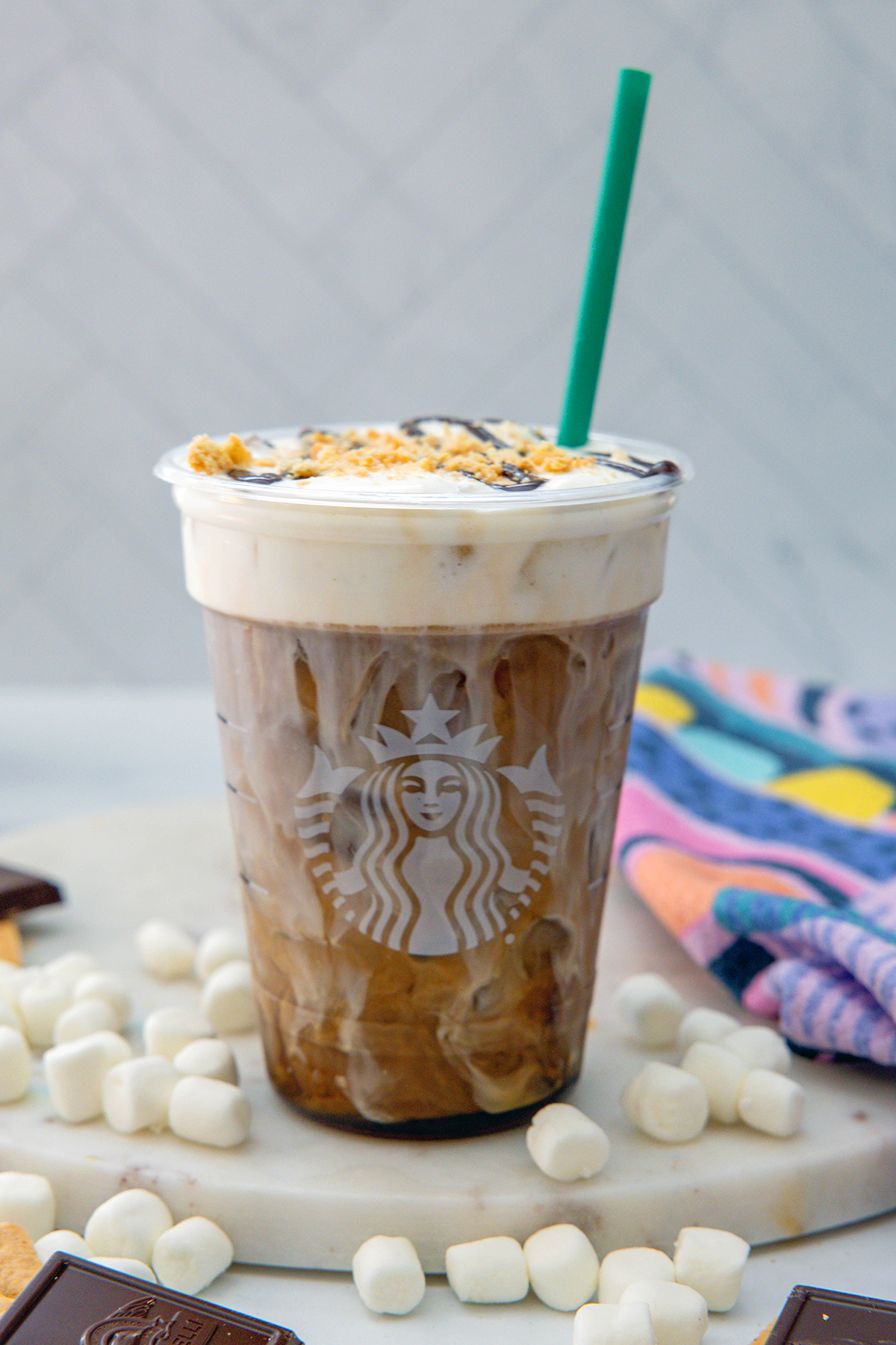 Head-on view of a S'mores Cold Brew with milk and coffee blending together and a green straw.