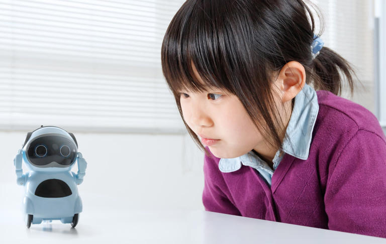 A young Japanese girl looks at a robot. Academics advocate imposing age limits on AI use. Photo: Getty Images